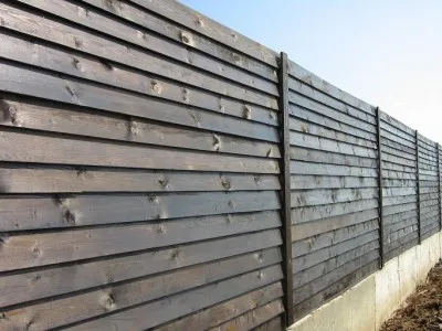 На фото: забор,где монтаж досок выполнен внахлест