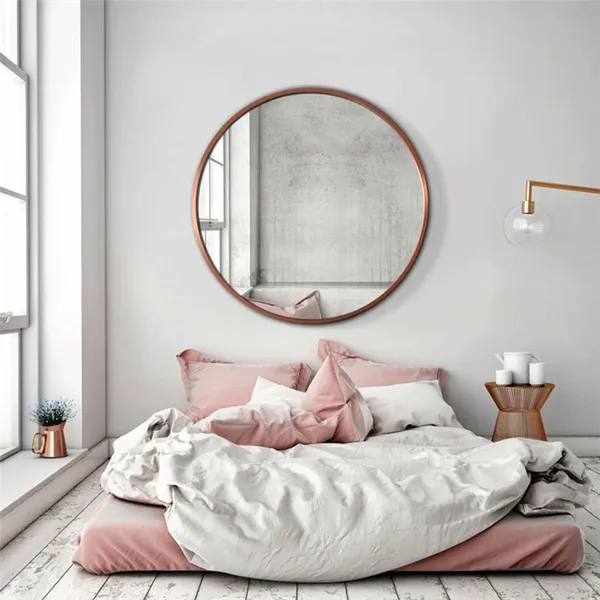 Светлая спальня с розовыми и медными акцентами. Над кроватью большое круглое зеркало Scandi в медной оправе от GieraDesign.
